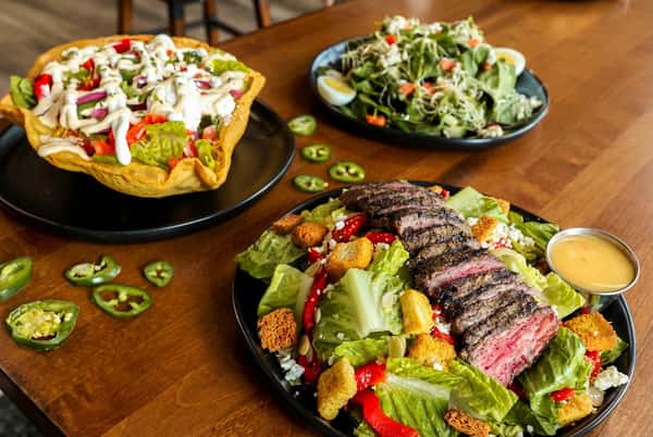 Meat dishes on a table with garnish topped on each plate
