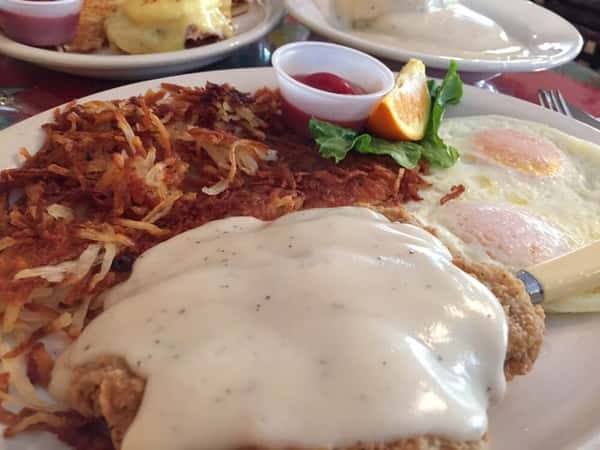 Chicken fried steak with gravy, hasbrowns and two fried eggs on a plate