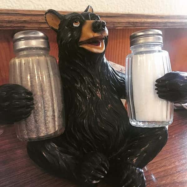 Wooden bear holding salt and pepper shakers on a table