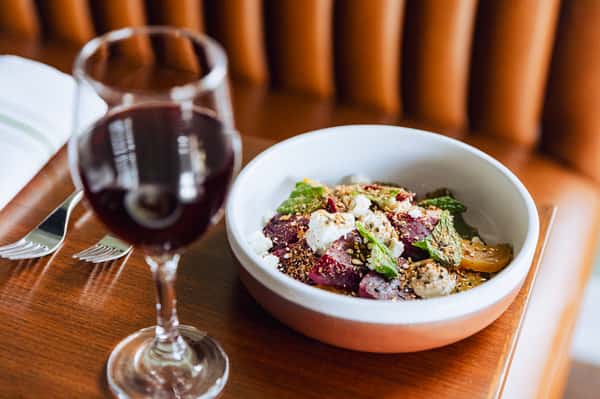 Bowl of food paired with a glass of red wine on a table