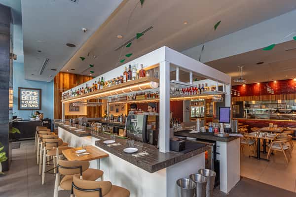 Modern restaurant bar and dining space featuring marble surfaces, wood accents, and bar seating.