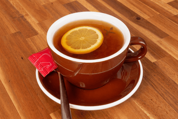 Hot tea served with a fresh lemon slice in a ceramic mug.