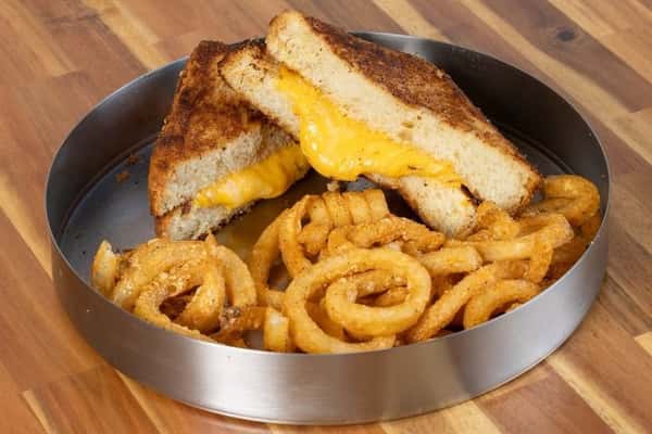 Grilled cheese sandwich served with crispy curly fries on a metal platter.