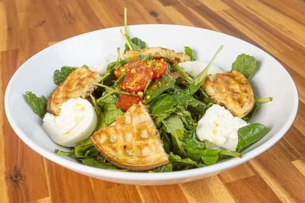 Mixed greens salad with grilled chicken, berries, and creamy cheese.
