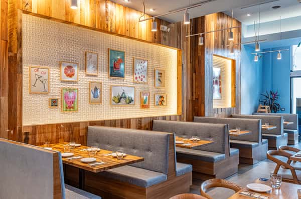Cozy restaurant booths and dining tables surrounded by warm wood finishes and colorful artwork.