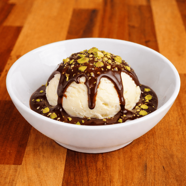 Vanilla ice cream drizzled with chocolate sauce and topped with crushed pistachios.