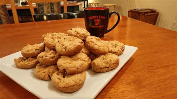 Chocolate chip cookies piled on a plate next to a cup of coffee