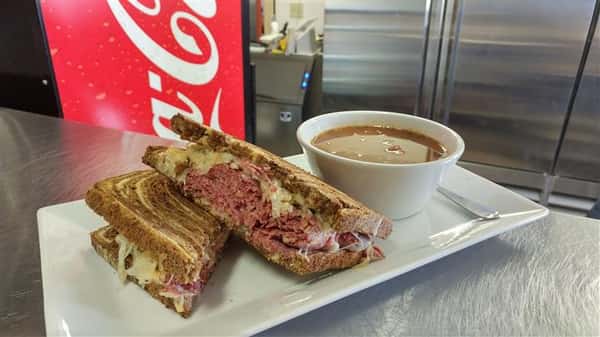Reuben sandwich served with side of gravy on a long plate