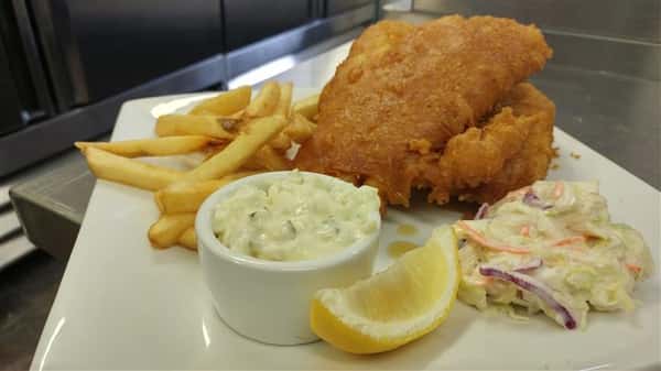 Fish and chips with tartar sauce, lemon, coleslaw on dish