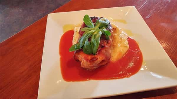 Chicken dish served with mashed potatoes and tomato sauce with a garnish of greens