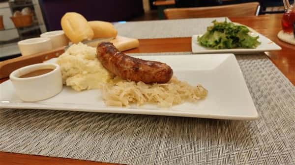 Bratwurst sausage served with sauerkraut and garlic mashed potatoes and gravy on the side