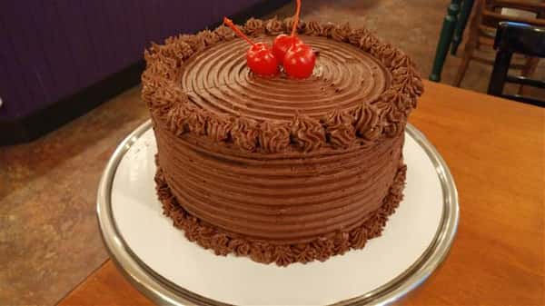 Chocolate cake decorated with chocolate frosting and cherries on top