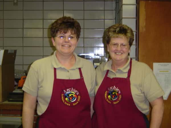 Two staff members wearing aprons smiling.