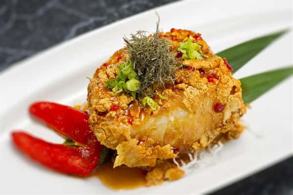 chunk of tempura white fish with scallions and chili flakes on top
