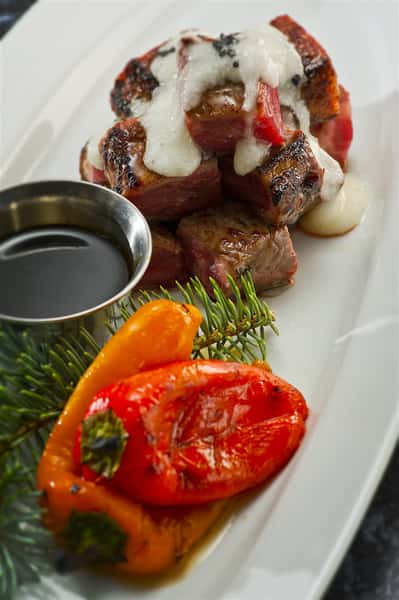 seared steak pieces served with a creamy sauce and roasted peppers