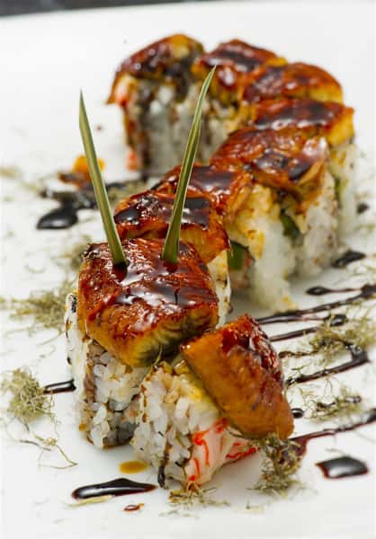 sushi roll with smoked eel on top cooked in a brown sauce