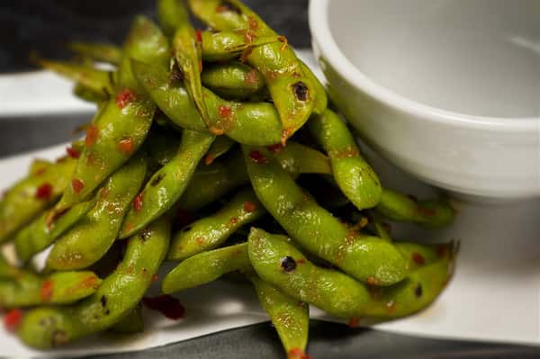 edamame beans with a spicy brown sauce on top