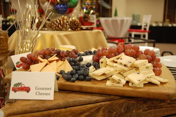 A beautifully arranged cheese platter features gourmet cheeses, red grapes, and blueberries, perfect for catering events.