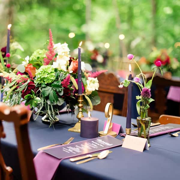 A beautifully arranged wedding table featuring a lush floral centerpiece, elegant candles, and personalized menus, set against a serene outdoor backdrop, perfect for a romantic celebration.