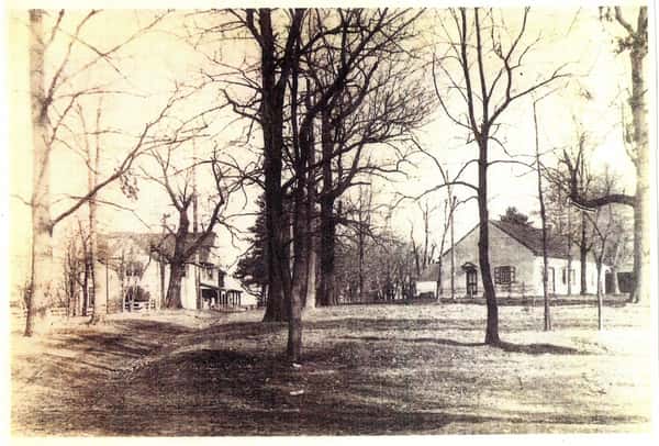 A historic black-and-white photo of Doe Run Catering shows a charming landscape with large trees and rustic buildings, evoking a warm, inviting atmosphere for gatherings and events.