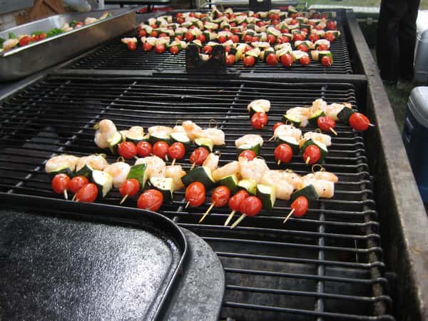 Grilled shrimp and vegetable skewers are arranged on a barbecue grill, showcasing vibrant cherry tomatoes and zucchini. Perfect for catering events and outdoor gatherings.