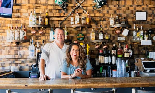 couple stands behind bar that they own