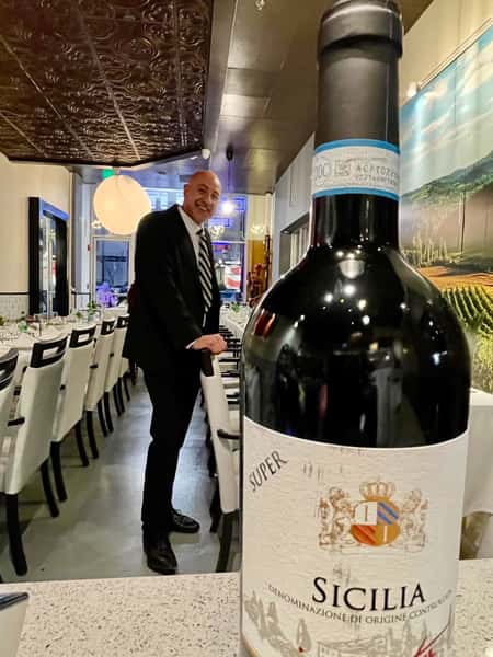 A wine bottle being held up in front of Chef Peter
