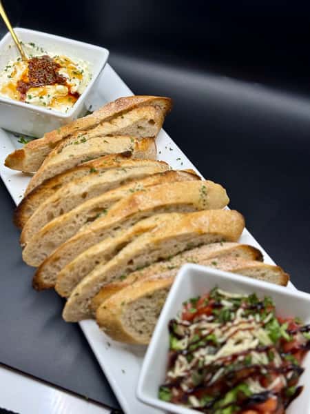 Sliced toasted baguette served with creamy dip topped with chili oil and a fresh tomato bruschetta mix with balsamic drizzle.