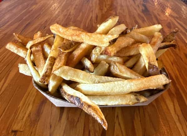 A basket of freshly fried potatoes sits on a wooden table at Main Street Eats.