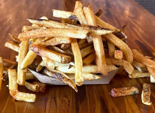 A basket of freshly fried potatoes sits on a wooden table at Main Street Eats.