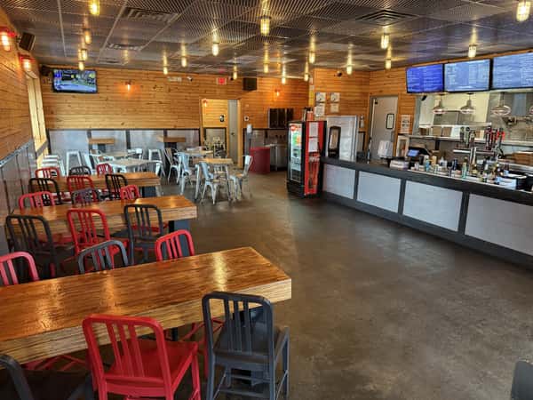 The interior of Main Street Eats restaurant shows empty tables and chairs awaiting customers, with a drink bar and menu boards visible.