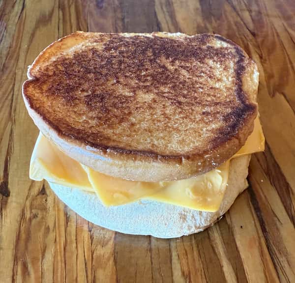 A toasted cheese sandwich on a wooden surface, ready to be served at Main Street Eats.