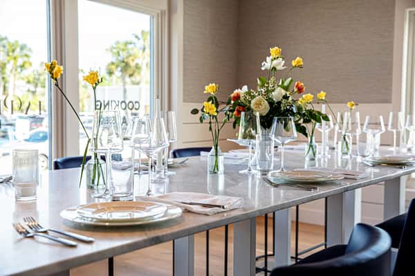 Dining table with flower vases, plates, glassware and silverware