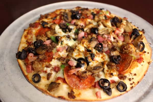 Specialty pizza topped with black olives, peppers, and cheese