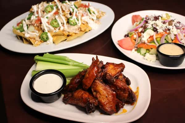 Collage of loaded nachos, a side salad, and a plate of glazed chicken wings with celery and dipping sauce