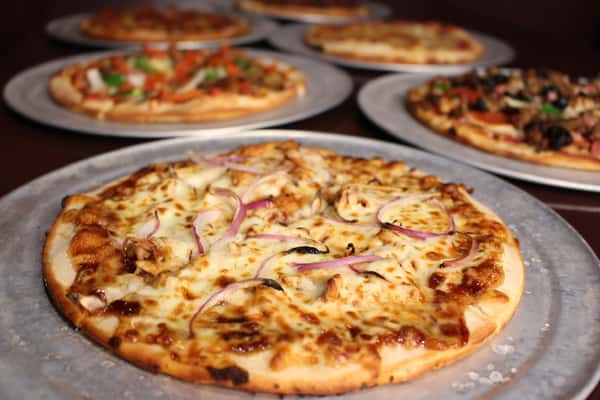 Cheese pizza fresh out of the oven, with additional pizzas in the background