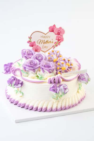 Mother's Day celebration cake with purple buttercream roses and floral piping, topped with a "Happy Mother's Day" sign, styled as an elegant custom bakery cake on a clean background.