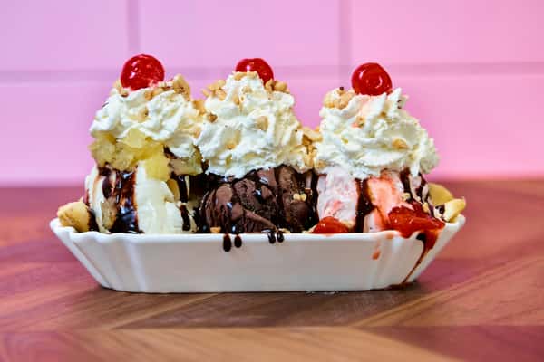 Banana split topped with whipped cream, cherries, strawberries, and chocolate sauce