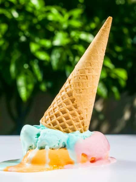 Mint ice cream cone outdoors with a blurred green background.