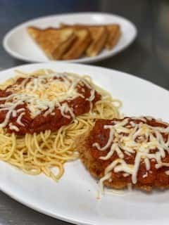 spaghetti topped with sauce and cheese with a side of chicken parmigiana topped with sauce and cheese