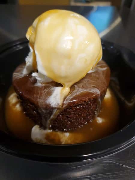 brownie topped with scoop of vanila ice cream and caramel sauce