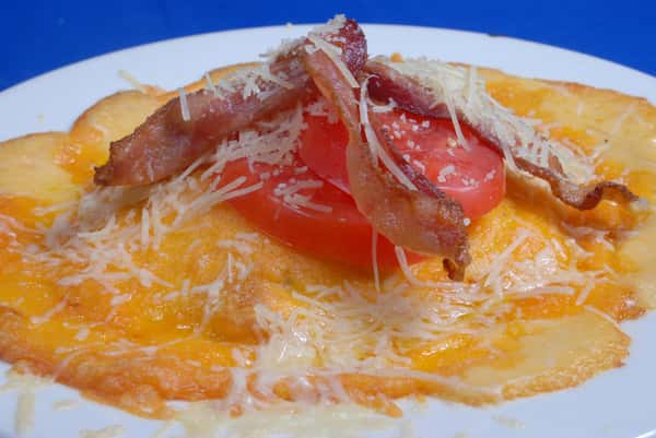 Melted cheese topped with tomato, grilled bacon and shredded cheese
