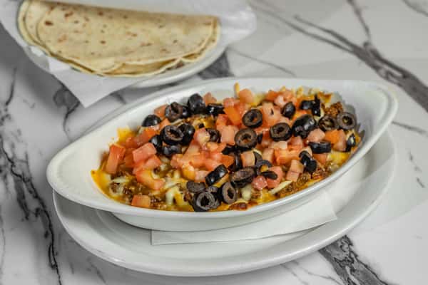 Baked queso fundido topped with chopped tomatoes and black olives, served with warm flour tortillas — savory melted cheese dip ideal for starters or shareables.