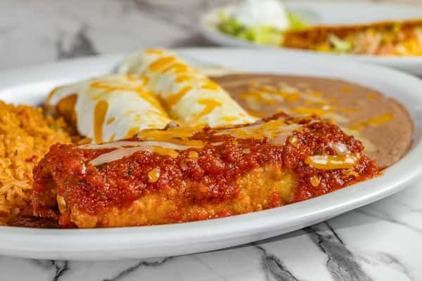 Close-up of a flavorful Mexican plate with red and white sauce enchiladas, refried beans, and seasoned Mexican rice.