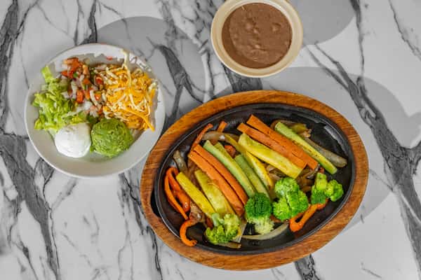 Sizzling vegetable fajitas with grilled onions, squash, carrots, and broccoli, served with refried beans, guacamole, sour cream, shredded cheese, and pico de gallo — colorful and customizable veggie entrée.