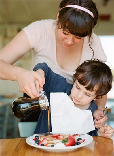 women helping her son pour syrup