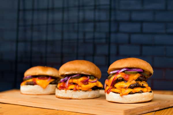 Indulge in three mouthwatering burgers loaded with cheese and toppings, perfect for food lovers.