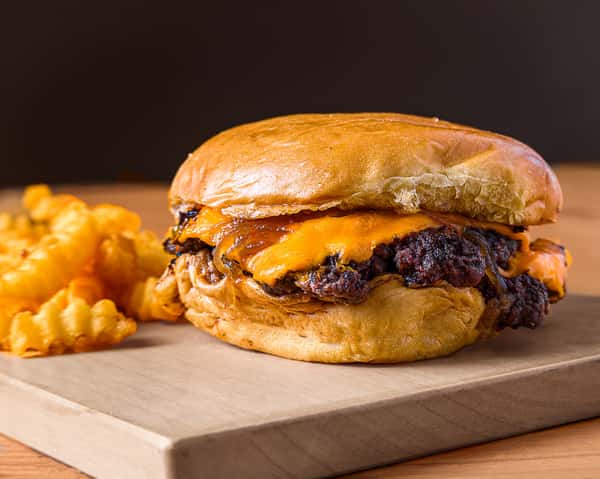 Tasty cheeseburger with crinkle-cut fries presented on a wooden board, perfect for fast food lovers.