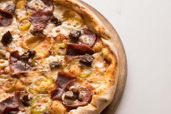 Freshly baked meat lovers pizza topped with pepperoni, ham, sausage, peppers, and melted mozzarella cheese.