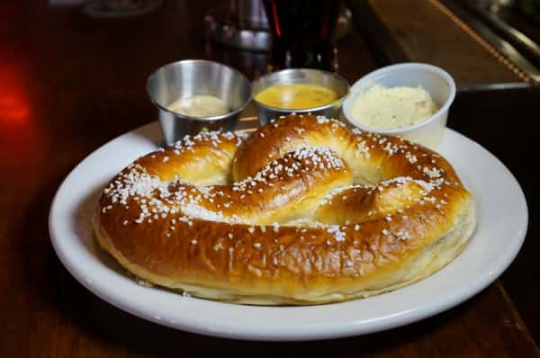 Warm soft pretzel sprinkled with coarse salt and served with mustard, cheese sauce, and butter dips.